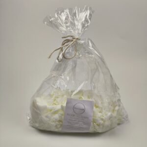 Przezroczysty woreczek z białymi płatkami naturalnego wosku sojowego, przewiązany sznurkiem jutowym, z okrągłą etykietą Warsztatownia