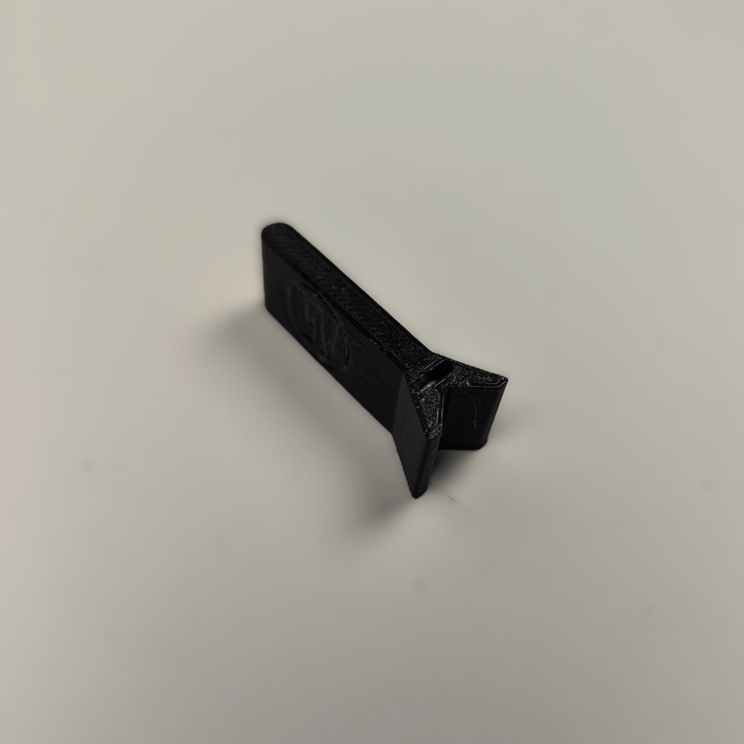 Magnetyczny uchwyt do gwoździ wykonany w technologii druku 3D z czarnego tworzywa, ułatwiający precyzyjne wbicie gwoździa bez narażania palców. Akcesorium ma formę płaskiego elementu z widocznym okrągłym zagłębieniem na magnes i szczeliną stabilizującą gwóźdź