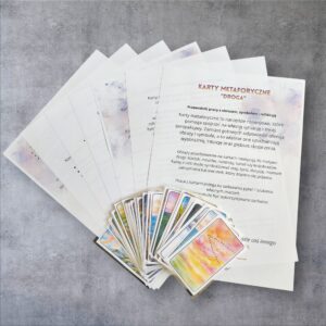 Półokrągły wachlarz kolorowych kart obrazkowych z akwarelowymi pejzażami ułożony na kartach z instrukcją pracy, na szarym tle