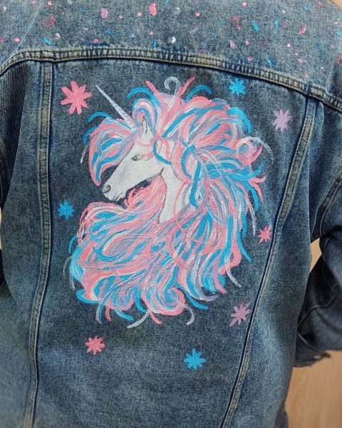 Kurtka jeansowa z ręcznie malowanym jednorożcem – tęczowa grzywa, różowe gwiazdki i niebieskie kropki na deniminowym tle, efekt warsztatów malowania ubrań