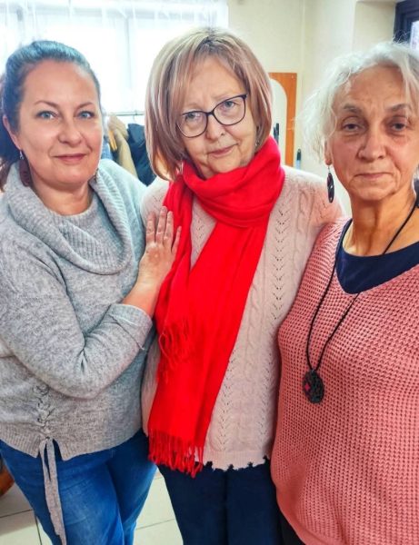 Trzy uśmiechnięte uczestniczki warsztatów Warsztatowni pozują razem, prezentując własnoręcznie wykonaną biżuterię. Monika Wojdyło