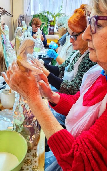 Uczestniczki warsztatów artystycznych w skupieniu modelują figurki z masy plastycznej podczas zajęć Warsztatowni