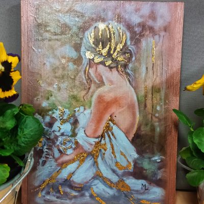 Pionowy obraz na drewnianym podkładzie przedstawiający kobietę z upiętymi włosami, odwróconą tyłem i trzymającą białe kwiaty. Postać ubrana jest w błękitną suknię zdobioną płatkami złotego szlagmetalu, który pojawia się również w jej włosach oraz na tło obrazu. Obraz stoi obok doniczek z żółtymi kwiatami